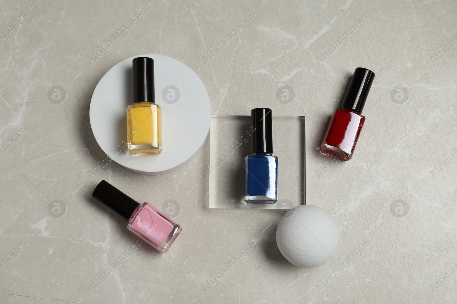Photo of Flat lay composition with bright nail polishes in bottles on light textured table