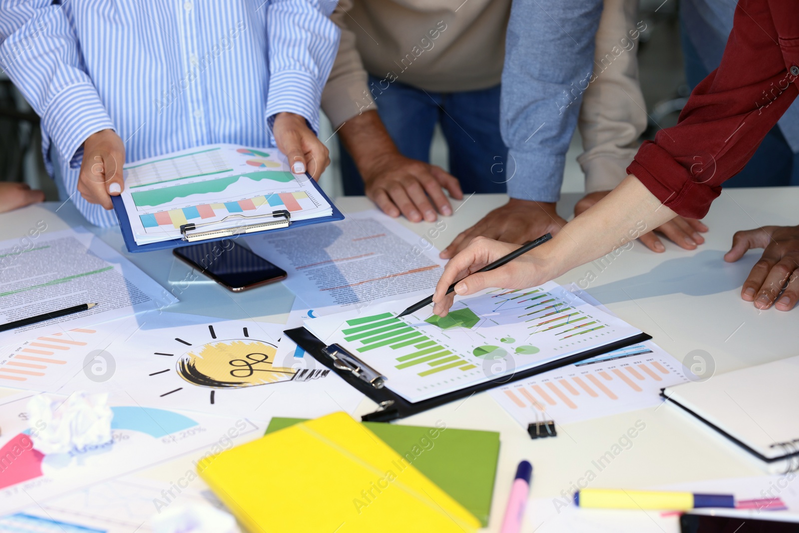 Photo of Team of employees working with charts at table, closeup. Startup project