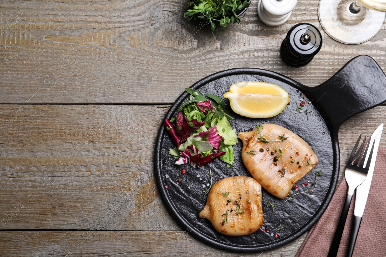 Photo of Grilled squid tubes served on wooden table, flat lay. Space for text