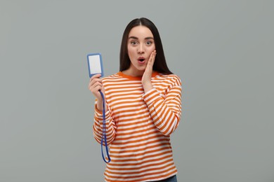 Emotional woman holding vip pass badge on grey background