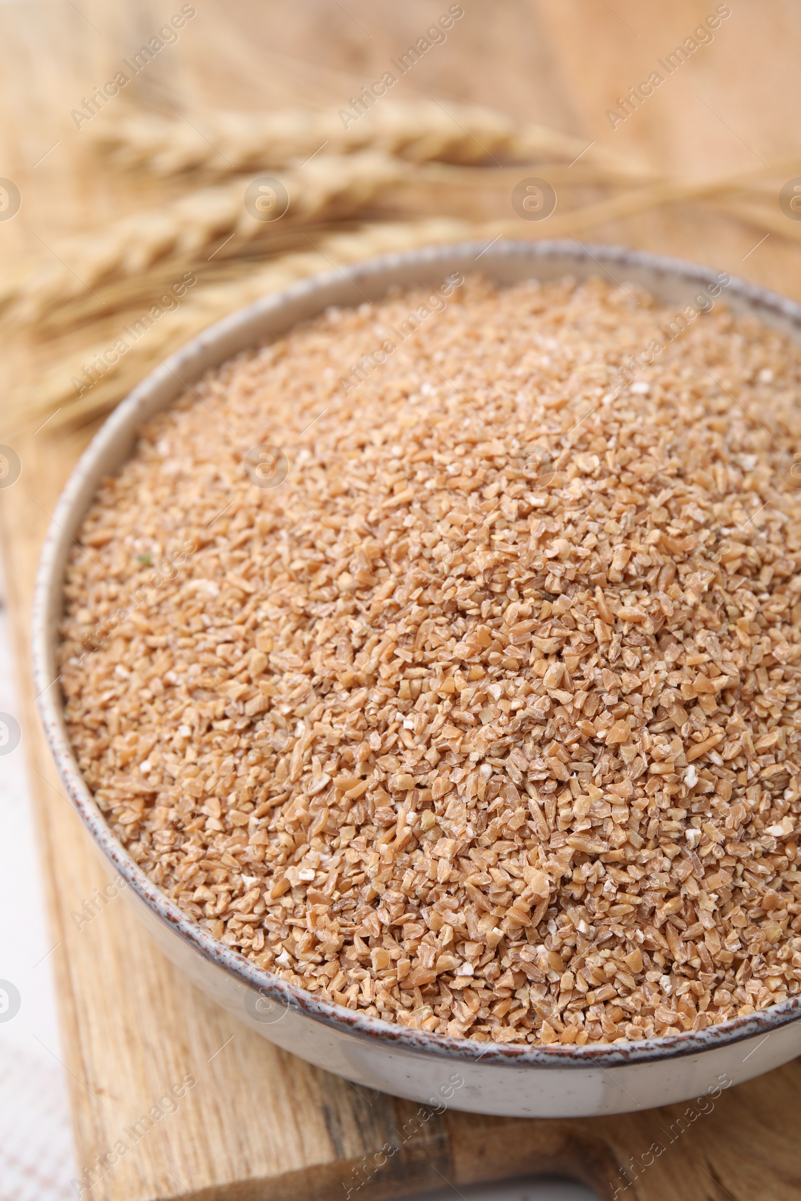 Photo of Dry wheat groats in bowl on table, closeup