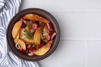 Photo of Delicious baked potato with thin dry smoked sausages, onion and dill in bowl on white tiled table, top view. Space for text