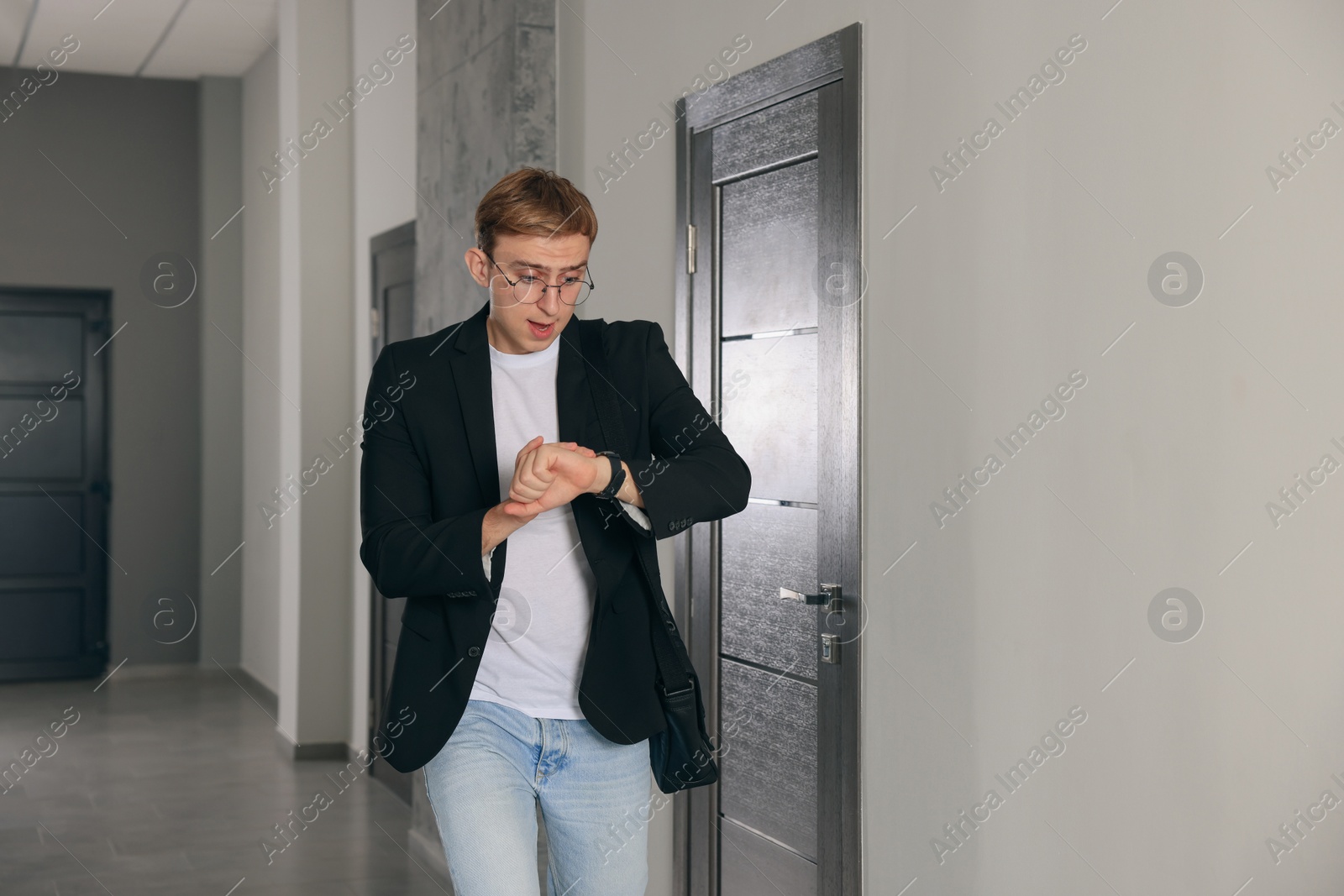Photo of Emotional man checking time in hall. Being late