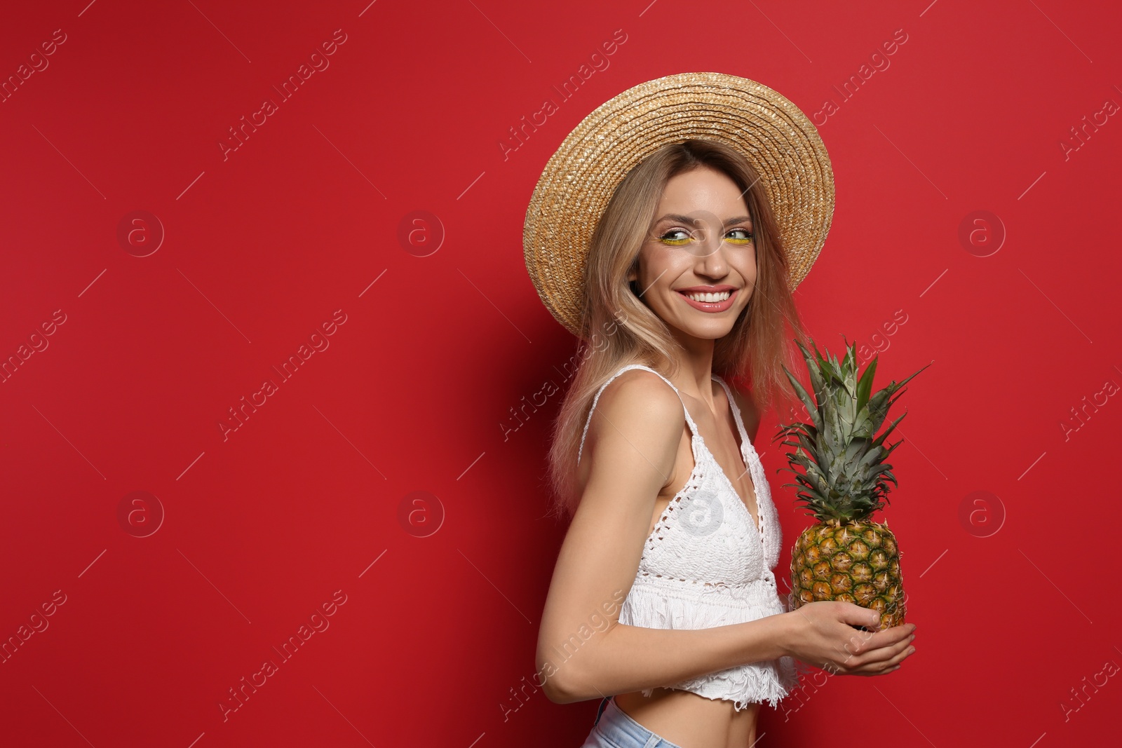 Photo of Young woman with fresh pineapple on red background, space for text. Exotic fruit