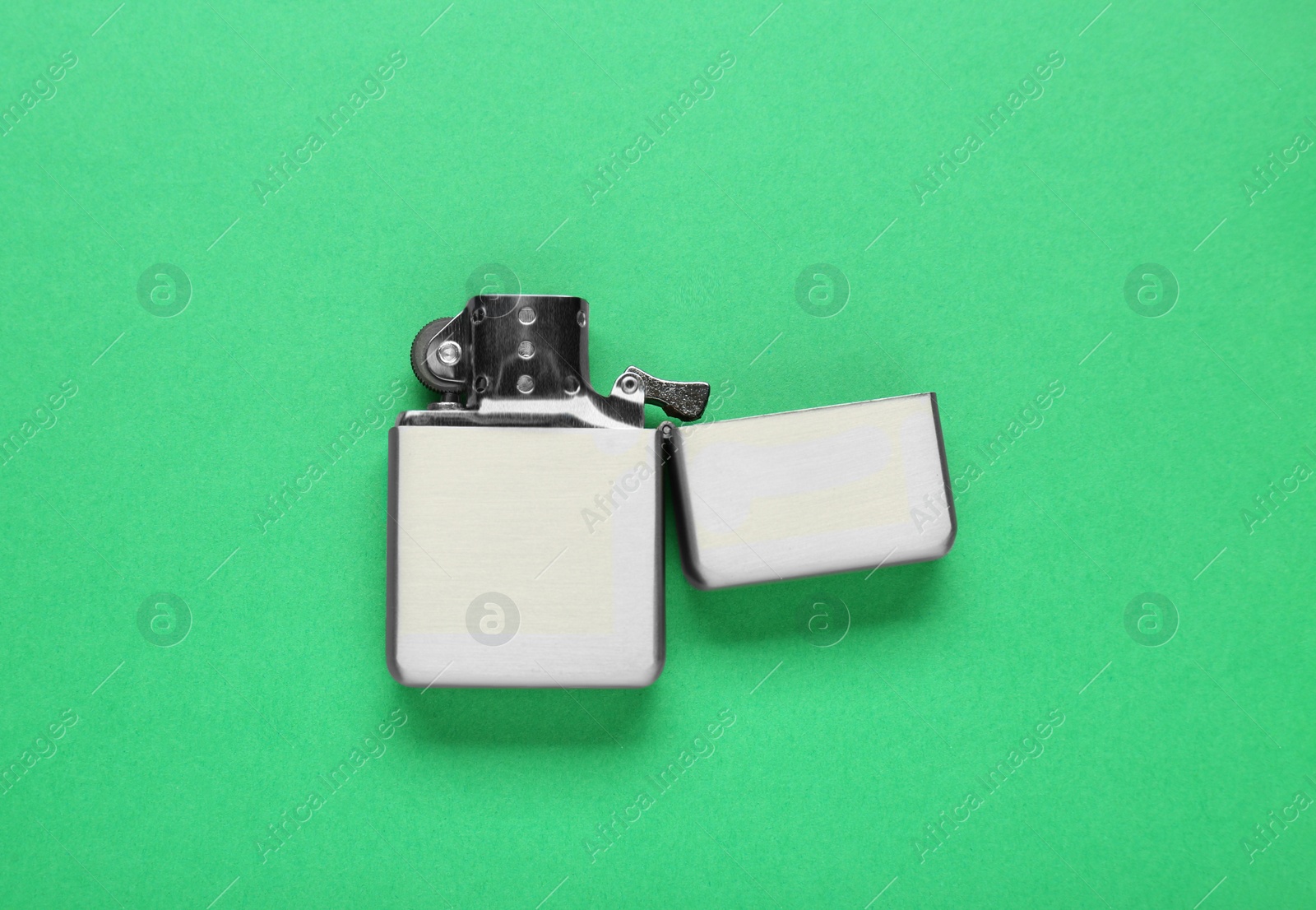 Photo of Gray metallic cigarette lighter on green background, top view