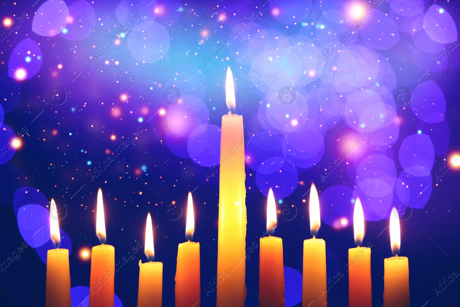 Image of Hanukkah celebration. Burning candles against dark blue background with blurred lights, closeup