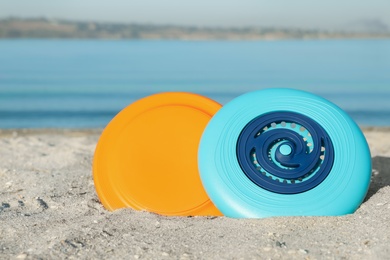 Plastic frisbee discs on sandy beach near river