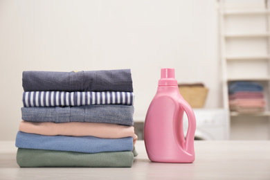 Stack of fresh laundry and detergent on white table in bathroom