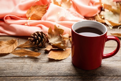 Photo of Cup of hot drink and leaves on wooden table. Cozy autumn atmosphere