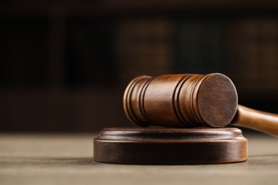 Photo of Wooden gavel on table against dark background, closeup
