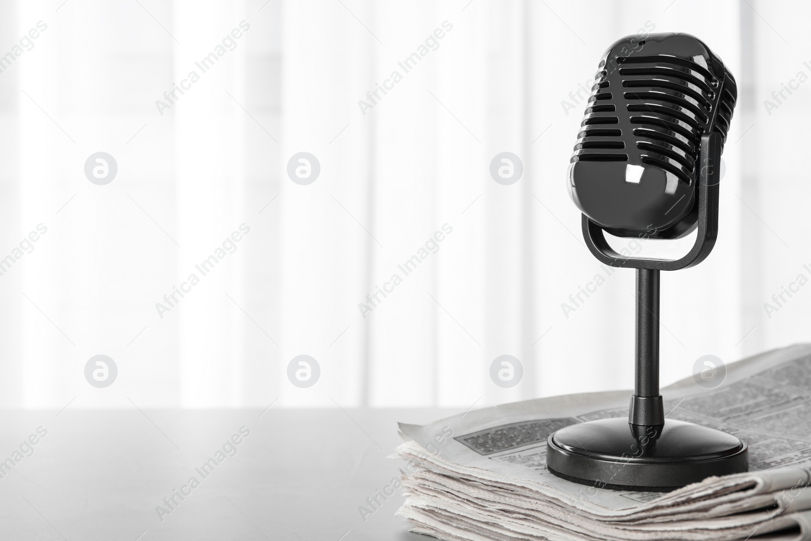 Photo of Newspapers and vintage microphone on grey table, space for text. Journalist's work