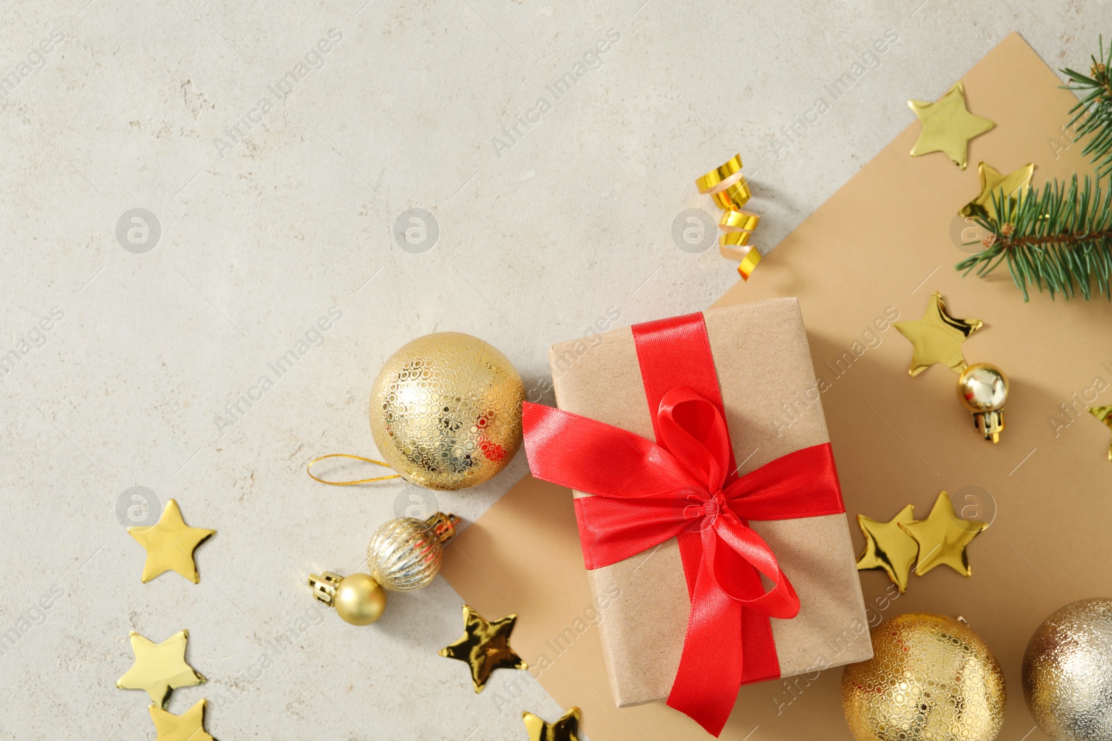 Photo of Flat lay composition with Christmas gift box and decor on light stone table, space for text