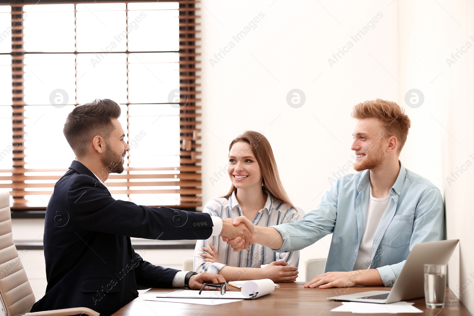 Photo of Insurance agent shaking hands with client in office