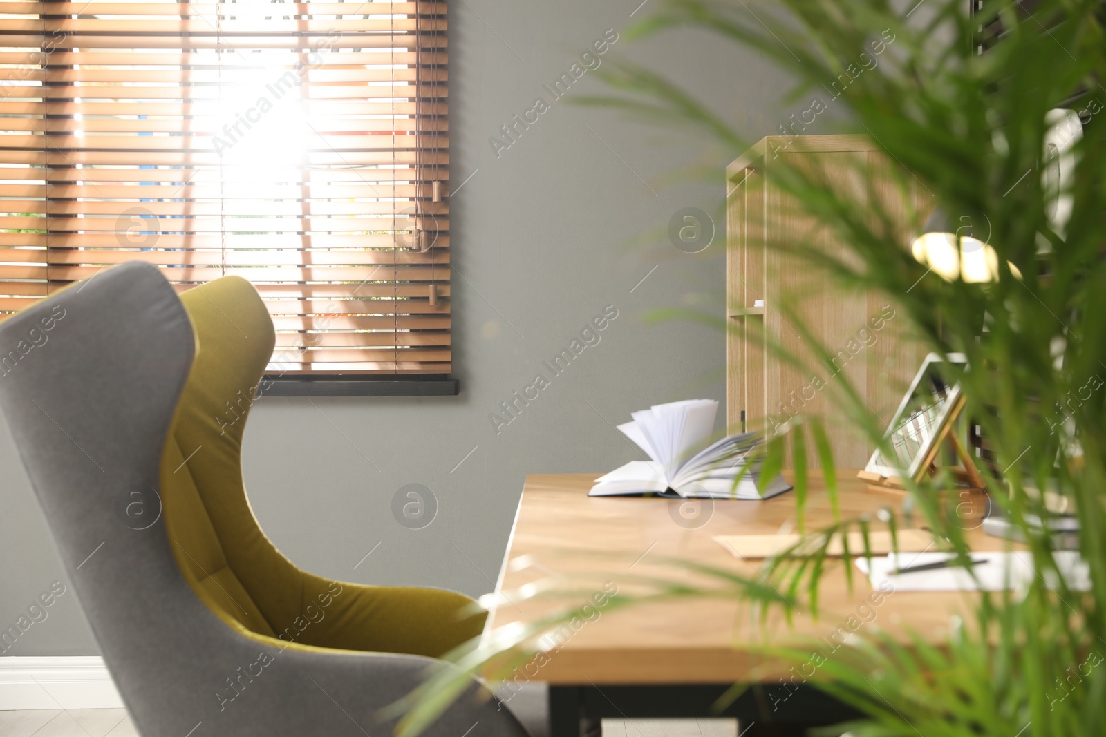 Photo of Comfortable workplace with wooden table and armchair