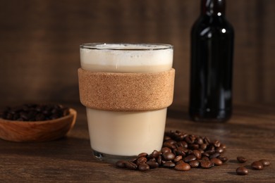 Photo of Bottle of delicious syrup, glass of coffee and beans on wooden table, closeup