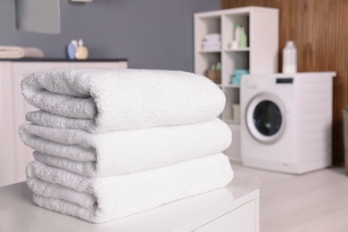 Photo of Stack of clean towels on table in laundry room. Space for text