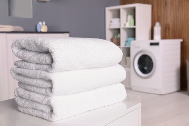 Stack of clean towels on table in laundry room. Space for text