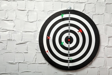 Arrows hitting dart board on white textured wall. Space for text