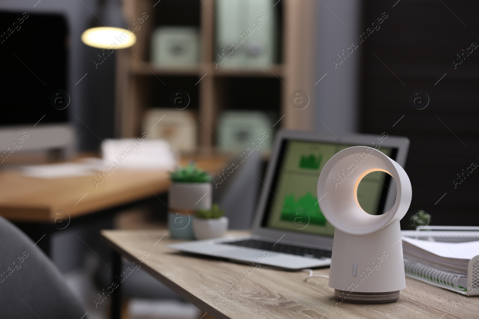 Photo of Modern electric fan on table in office. Space for text