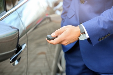 Photo of Closeup view of man opening car door with remote key