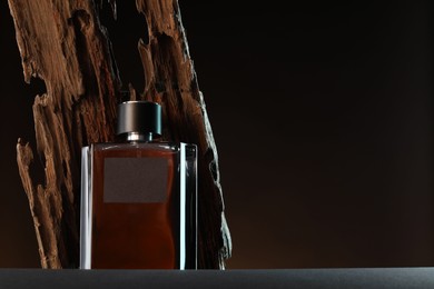 Photo of Luxury men`s perfume in bottle on grey table against dark background, space for text