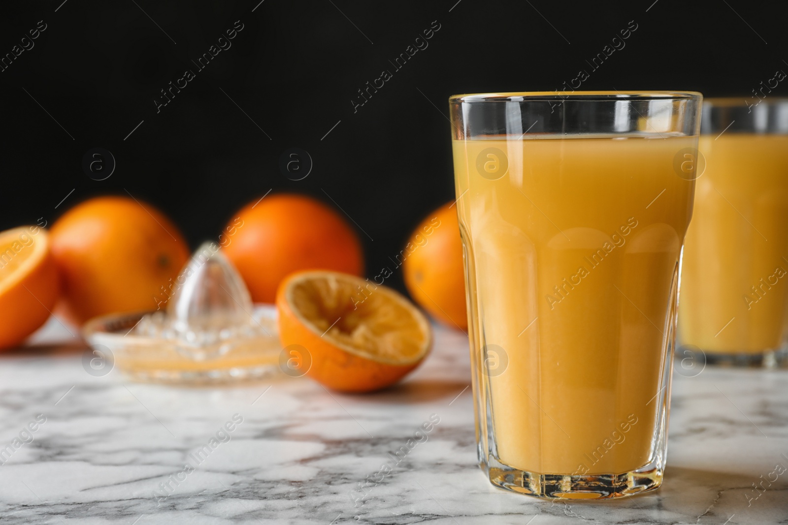 Photo of Glasses of orange juice on marble table. Space for text