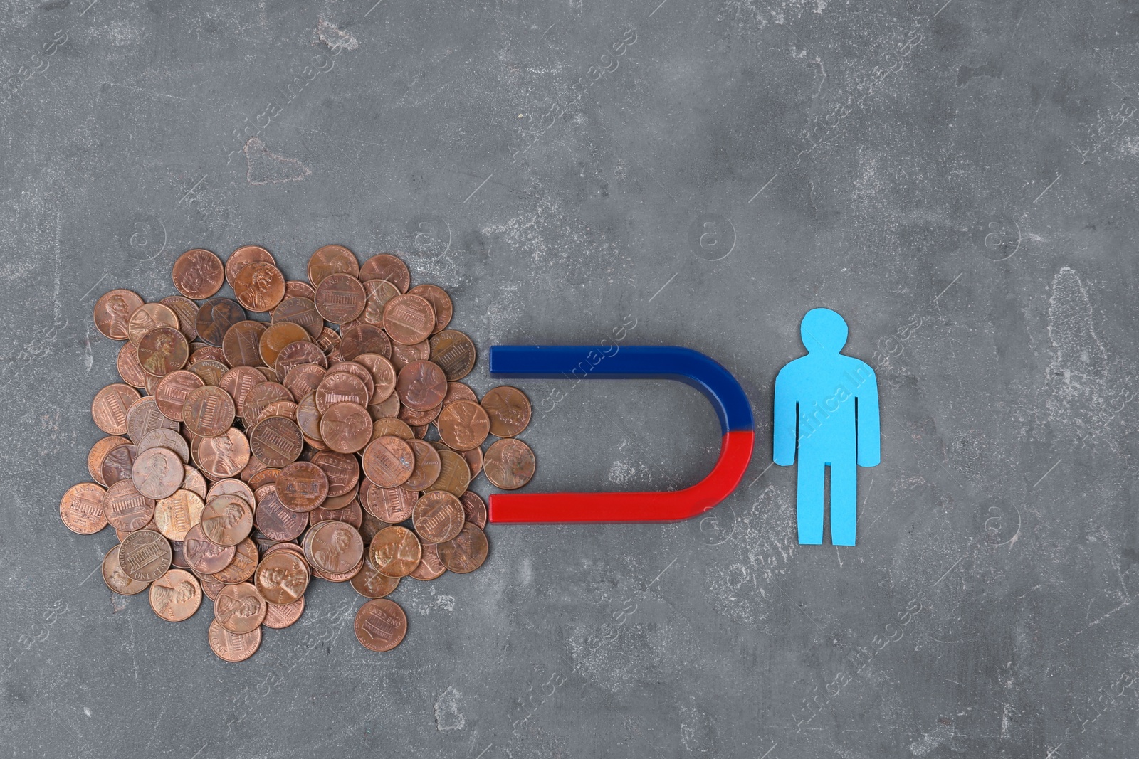 Photo of Paper person and magnet attracting coins on grey stone table, flat lay