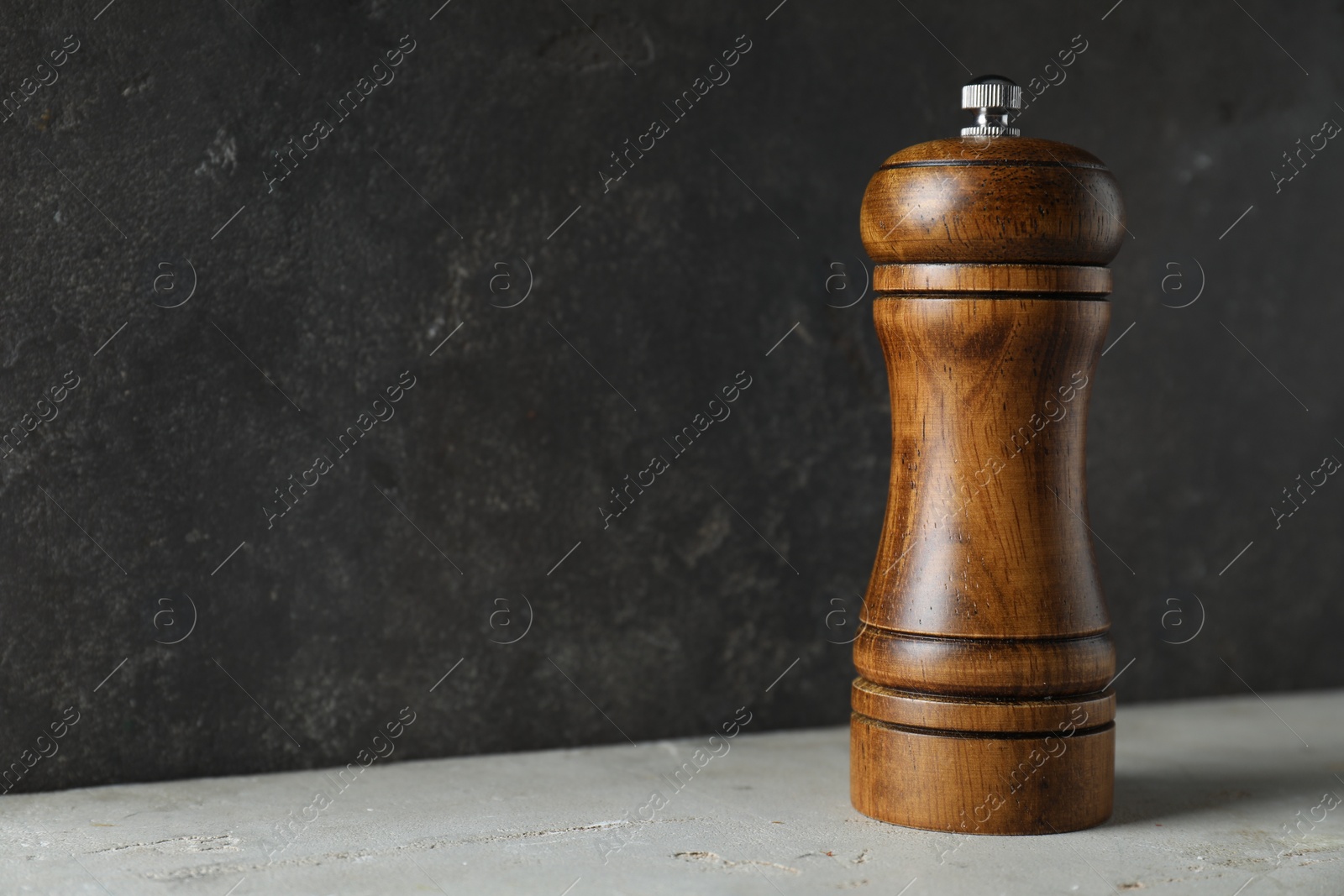 Photo of Wooden shaker on light table against grey background, closeup. Space for text