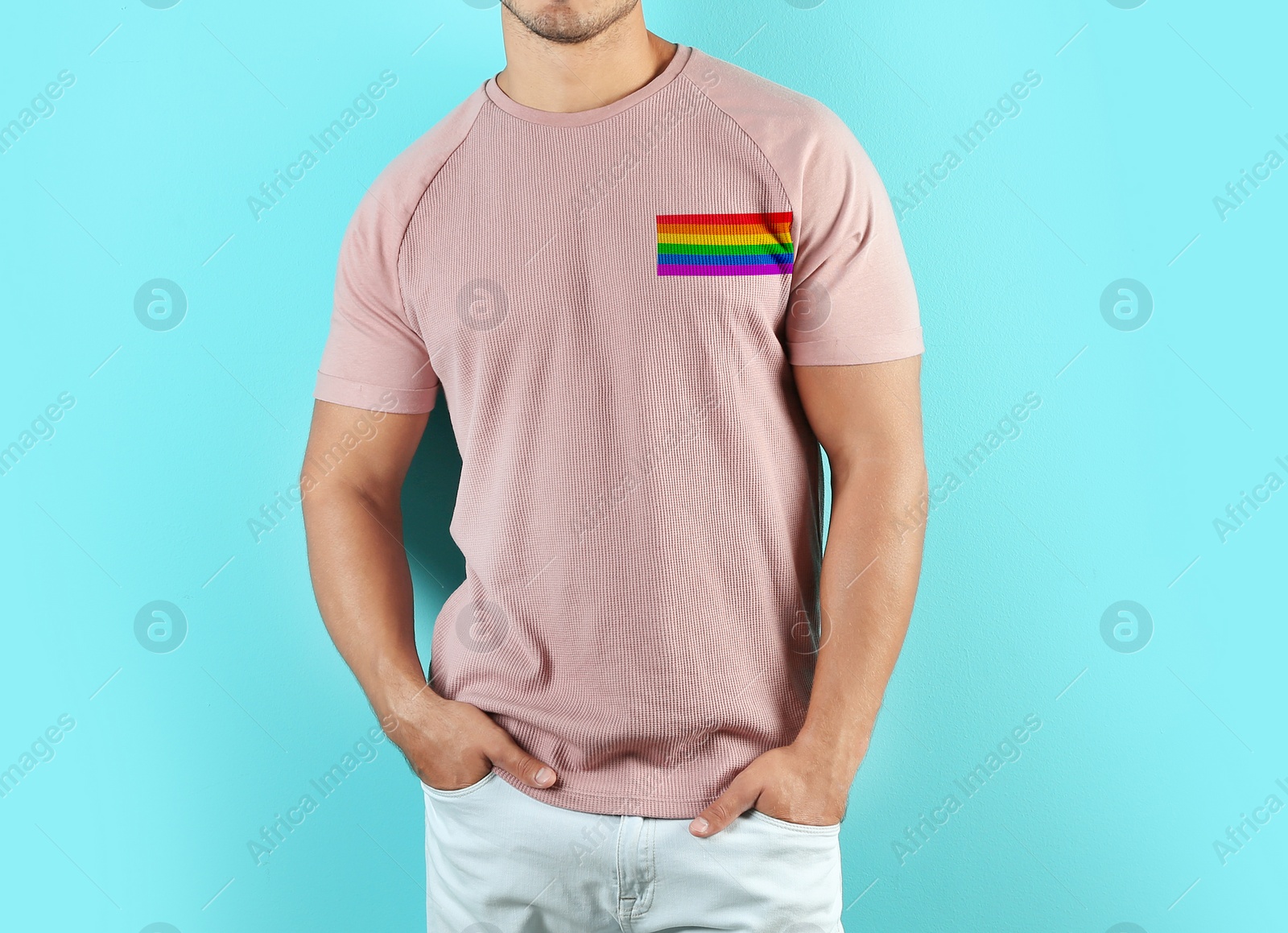 Image of Young man wearing pink t-shirt with image of LGBT pride flag on turquoise background