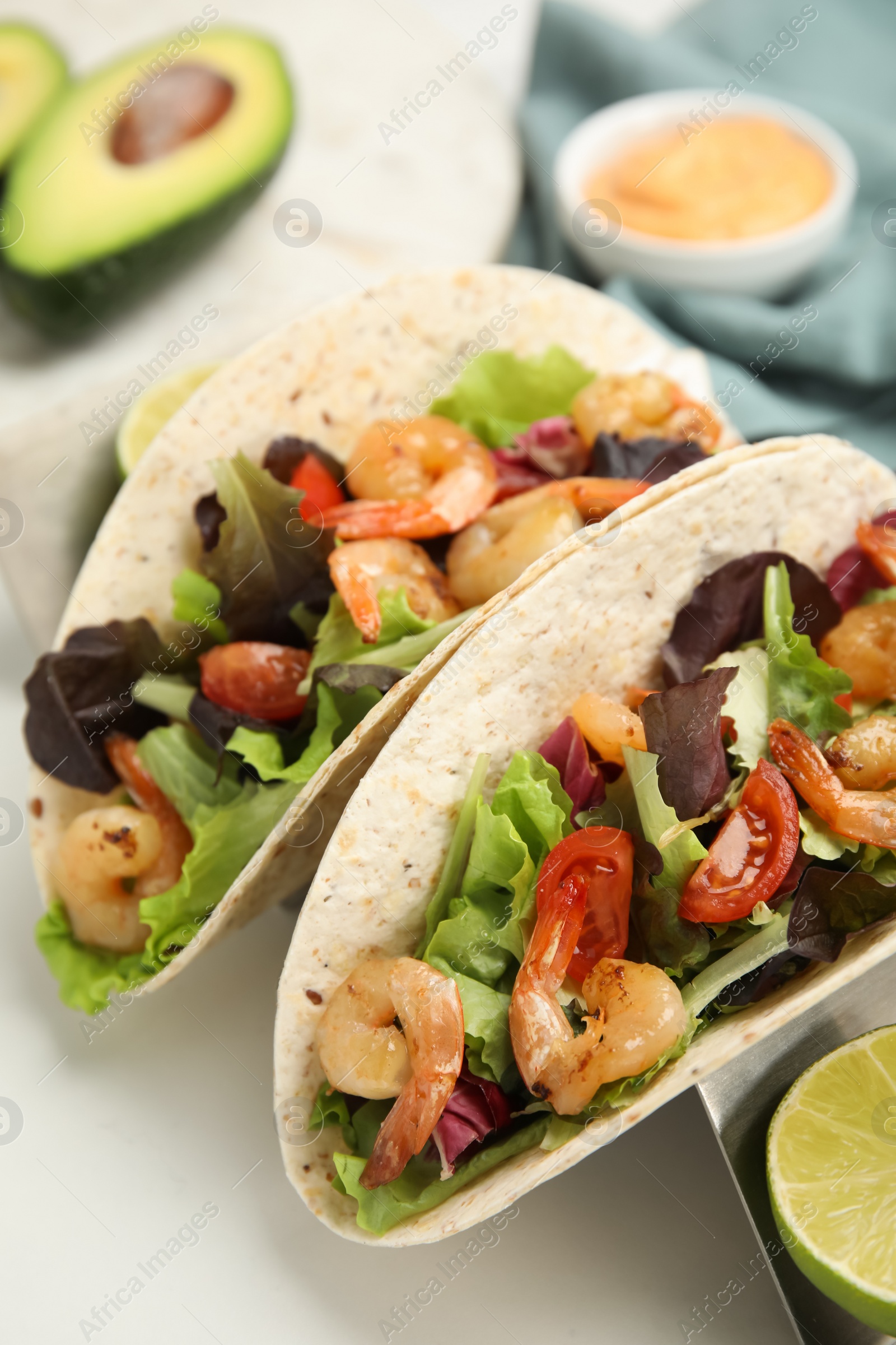 Photo of Delicious tacos with shrimps and lime on white table, closeup