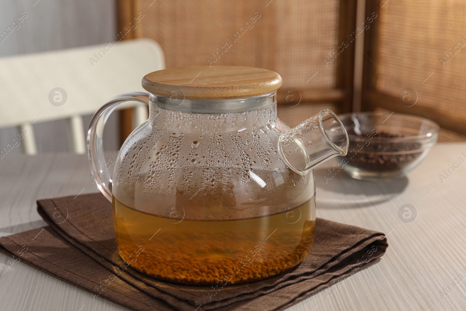 Photo of Glass teapot with aromatic buckwheat tea and granules on wooden table