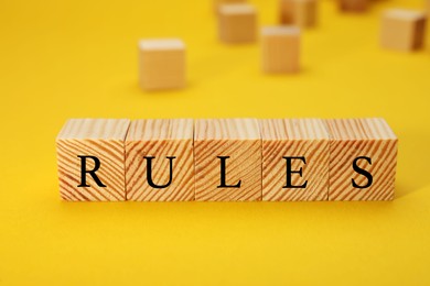 Photo of Word Rules made of wooden cubes with letters on yellow background