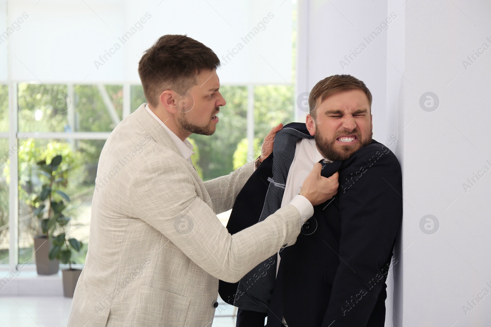 Photo of Emotional colleagues fighting in office. Workplace conflict