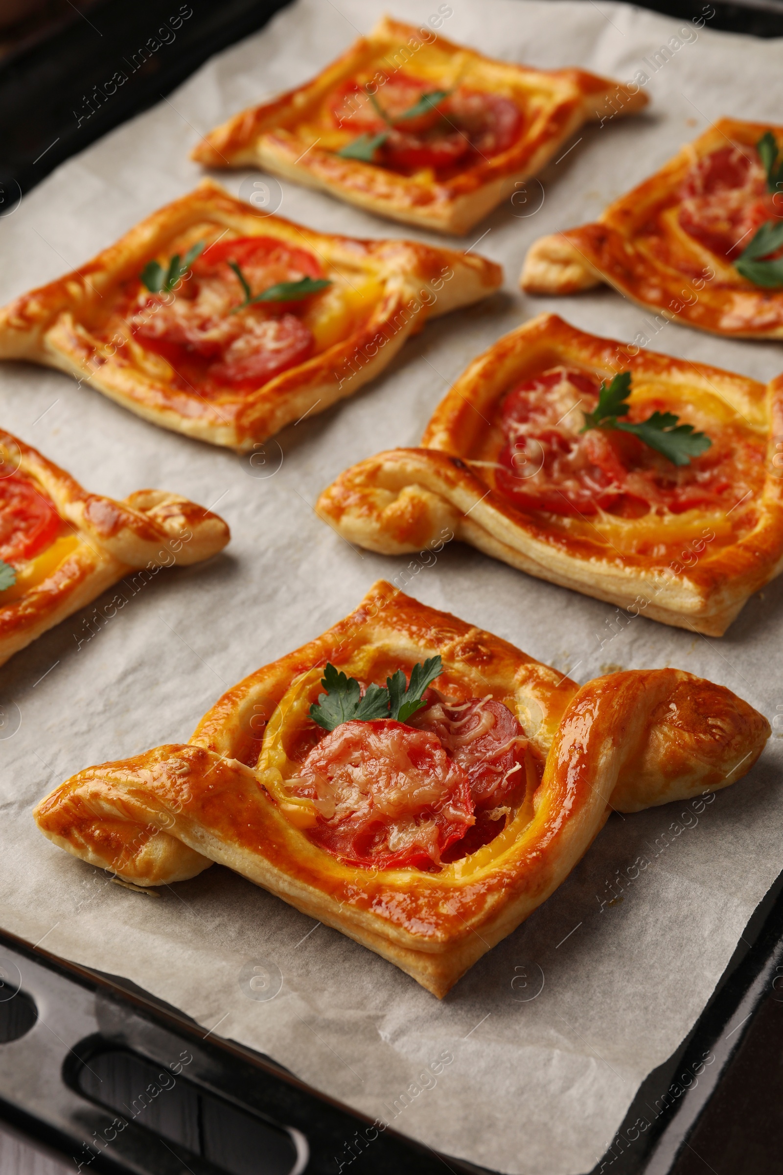 Photo of Fresh delicious puff pastry with tasty filling on baking sheet, closeup