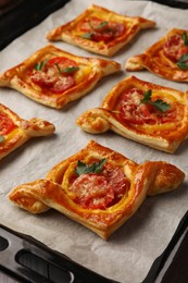 Fresh delicious puff pastry with tasty filling on baking sheet, closeup