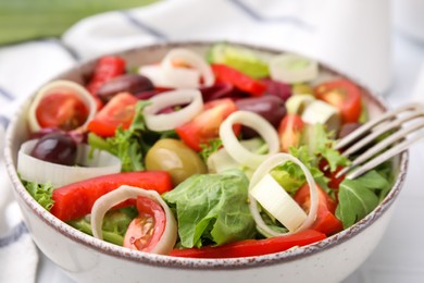 Photo of Bowl of tasty salad with leek and olives on table, closeup