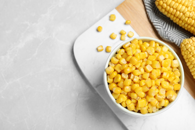 Photo of Delicious canned corn in bowl on marble table, flat lay. Space for text