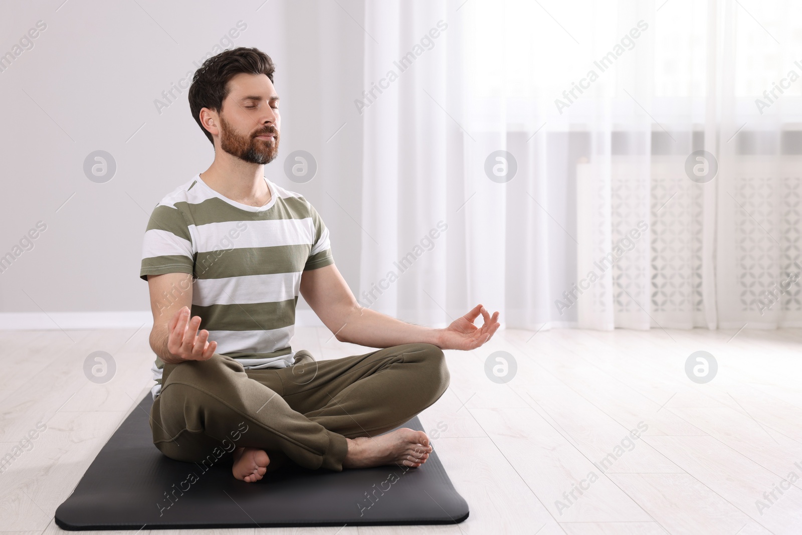 Photo of Man meditating at home, space for text