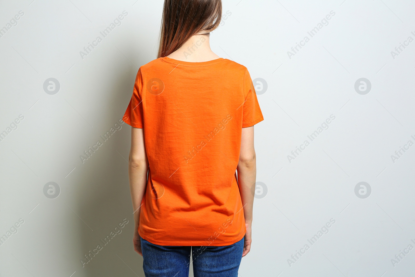 Photo of Back view of young woman wearing blank t-shirt on light background, closeup. Mockup for design