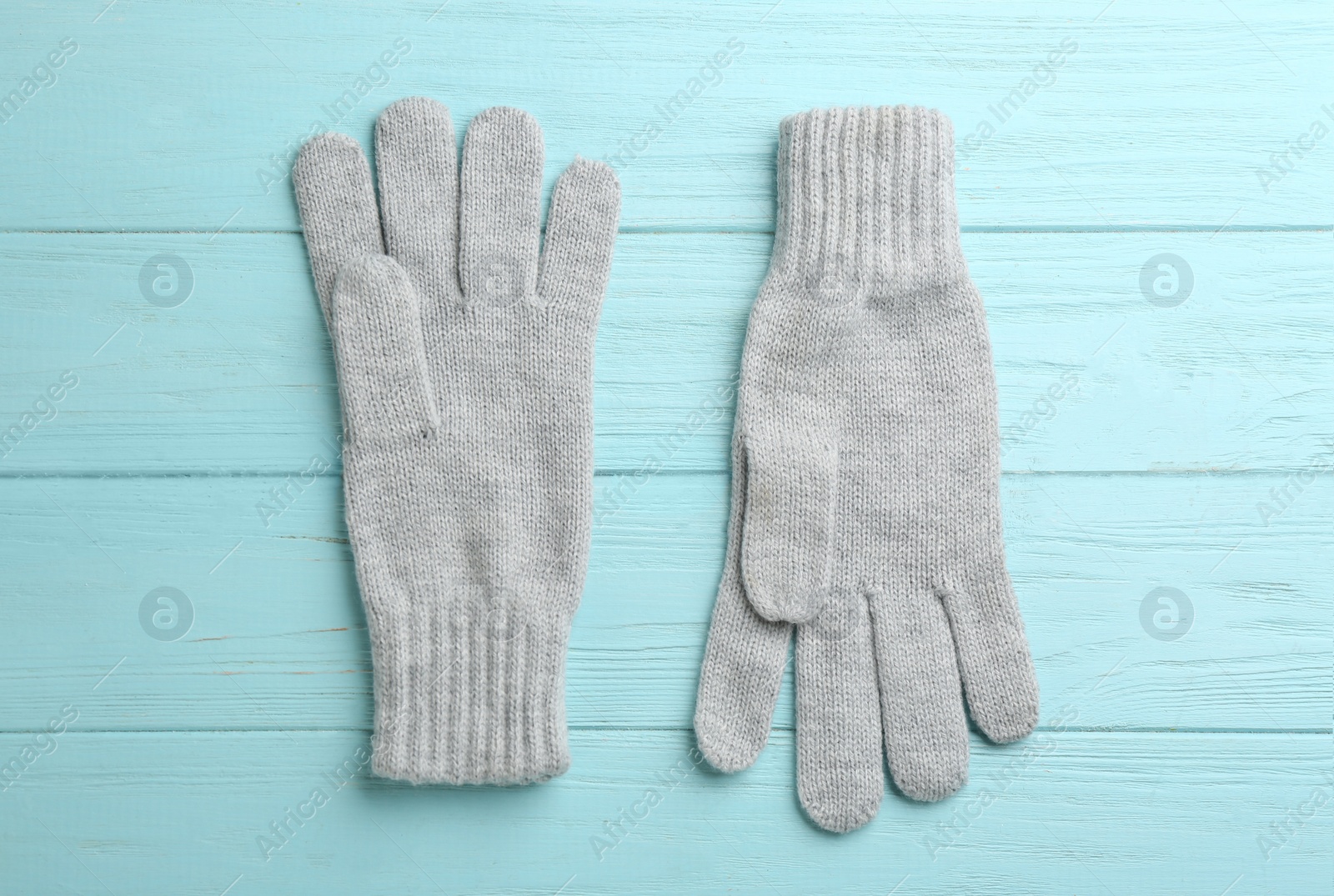 Photo of Pair of stylish woolen gloves on light blue wooden background, flat lay