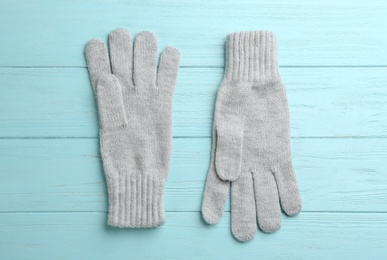 Pair of stylish woolen gloves on light blue wooden background, flat lay