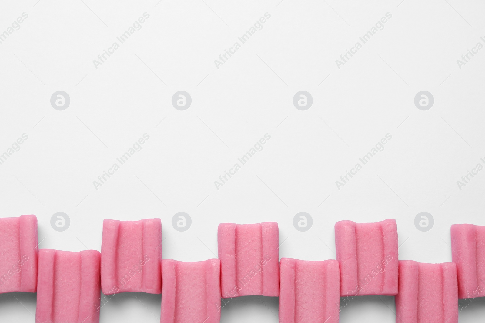 Photo of Tasty pink chewing gums on white background, flat lay. Space for text