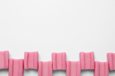 Photo of Tasty pink chewing gums on white background, flat lay. Space for text