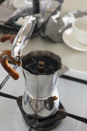 Photo of Brewing aromatic coffee in moka pot on stove indoors