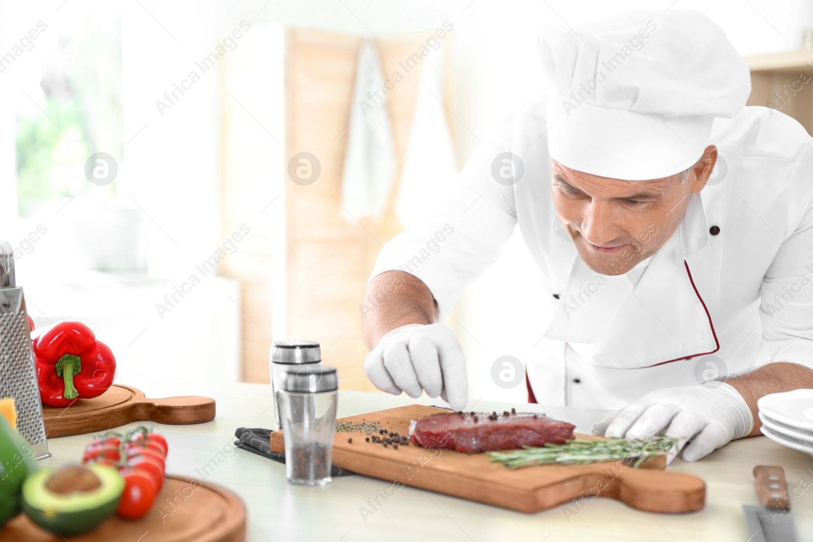 Photo of Professional chef cooking meat on table in kitchen