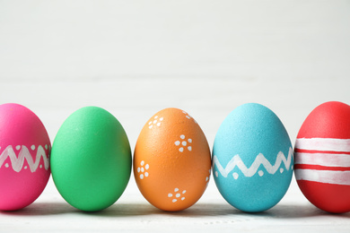 Photo of Colorful Easter eggs on white wooden background. Space for text