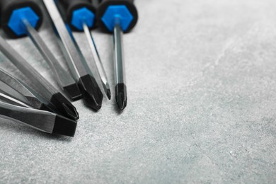 Set of screwdrivers on grey textured table, closeup. Space for text