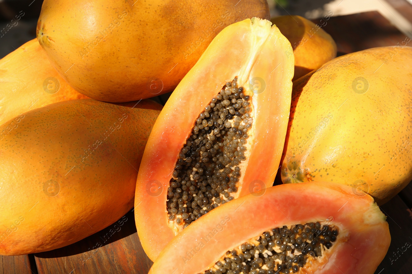 Photo of Fresh ripe cut and whole papaya fruits on wooden table, closeup