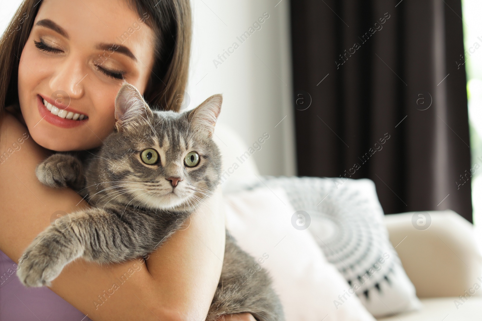 Photo of Young woman with cute cat at home, space for text. Pet and owner