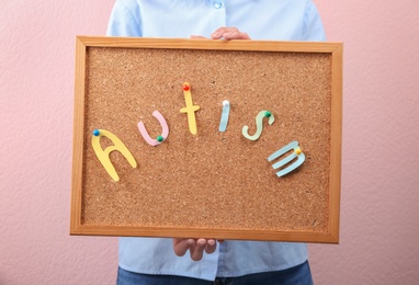 Photo of Woman holding board with word "Autism" on color background